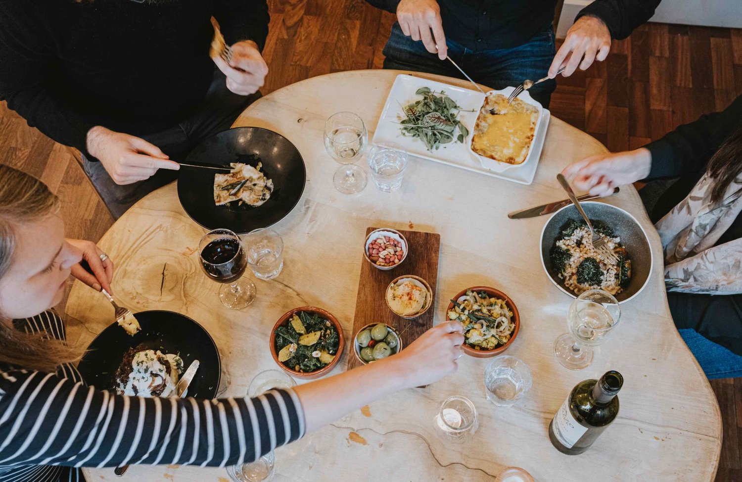 An overhead spread of shared vegetarian plates, bowls and wine on a timber table at Hendersons