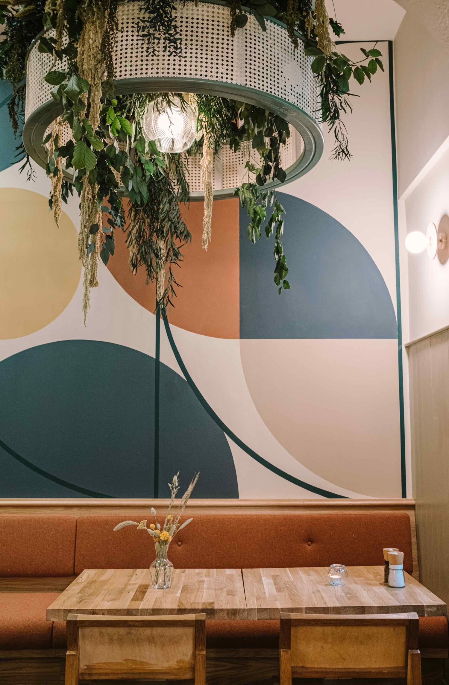 A laid table beneath the arched botanical mural at Hendersons